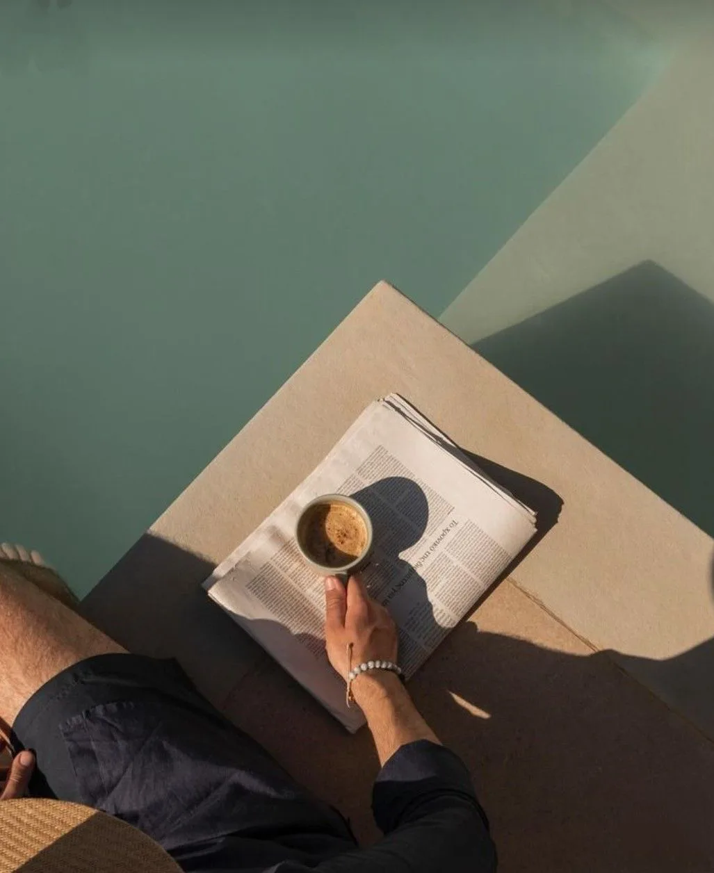 Un café posé sur le journal au bord de la piscine
