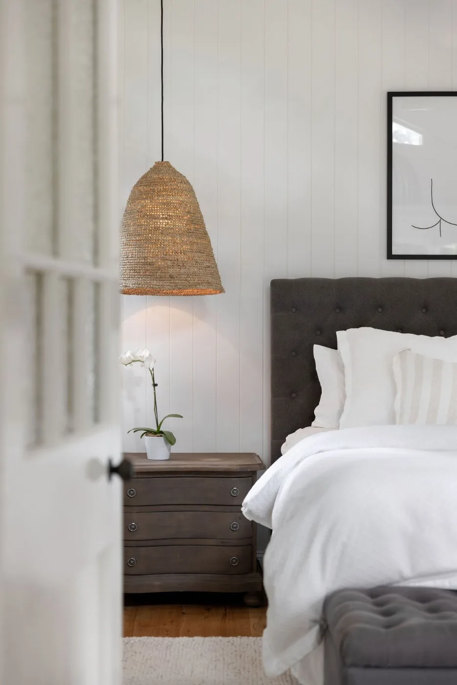 Chambre de gîte préparée : lit blanc, suspension en fibre, orchidée