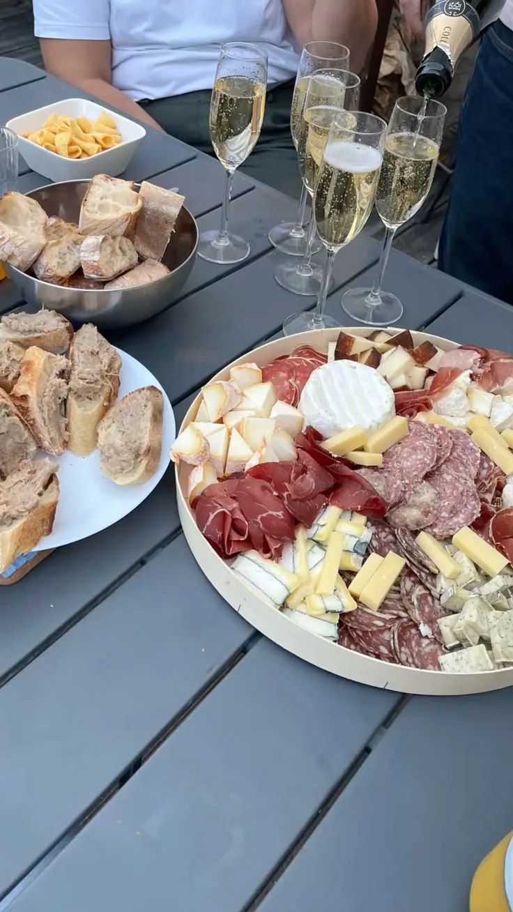 Planche charcuterie-fromage et coupes de champagne servies en terrasse